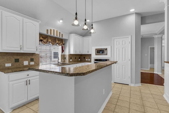 kitchen featuring white cabinetry, stainless steel microwave, dark stone counters, and oven