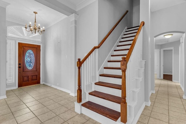 entryway with an inviting chandelier, baseboards, arched walkways, and crown molding