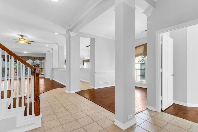 tiled foyer with ornamental molding, a ceiling fan, ornate columns, and stairs