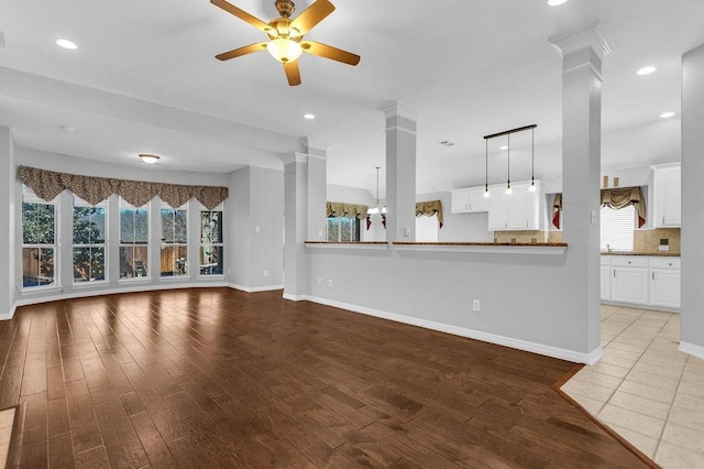 unfurnished living room with baseboards, ceiling fan, wood finished floors, ornate columns, and recessed lighting