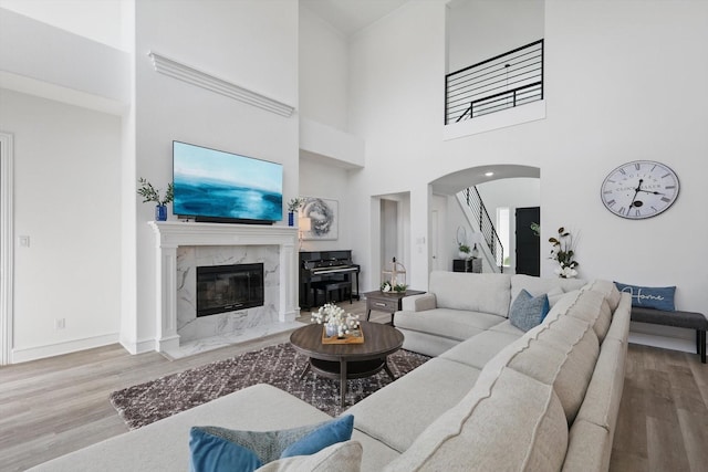 living area featuring arched walkways, a fireplace, stairway, and wood finished floors