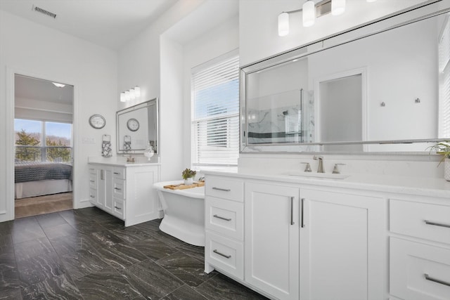 ensuite bathroom with two vanities, a sink, visible vents, a freestanding bath, and walk in shower