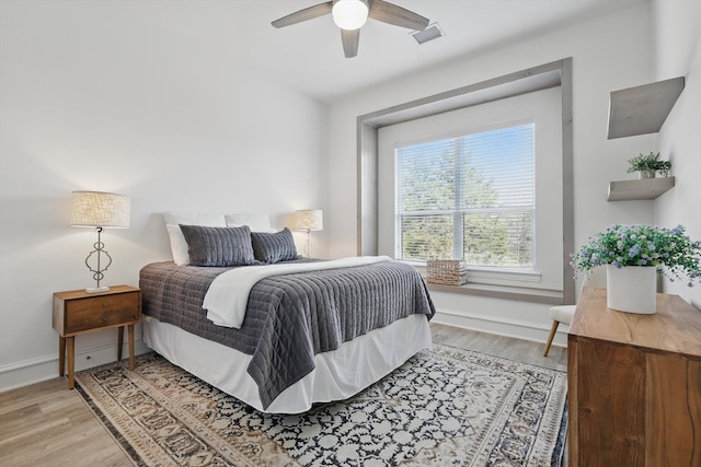 bedroom featuring a ceiling fan, light wood-type flooring, visible vents, and baseboards