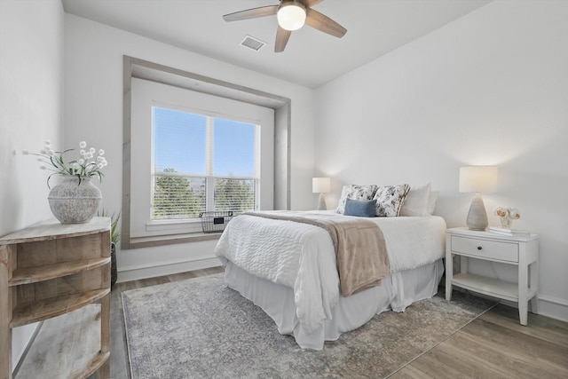 bedroom featuring a ceiling fan, baseboards, visible vents, and wood finished floors