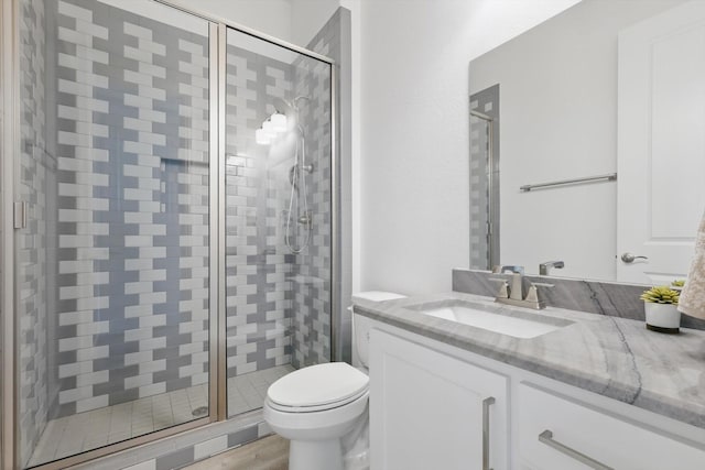 bathroom with vanity, wood finished floors, a shower stall, and toilet