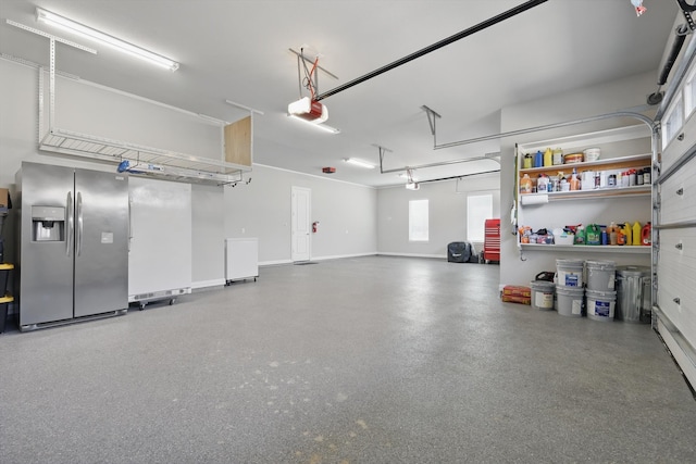 garage with baseboards, a garage door opener, and stainless steel fridge with ice dispenser