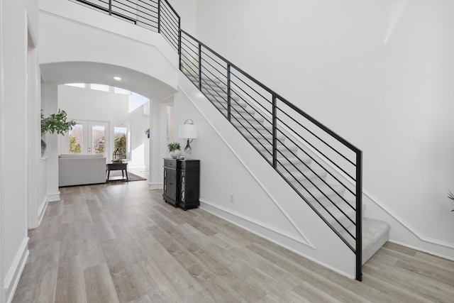 interior space with baseboards, arched walkways, wood finished floors, a high ceiling, and french doors