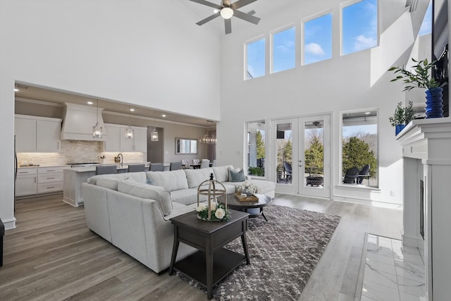 living area featuring a fireplace with flush hearth, french doors, wood finished floors, and a ceiling fan