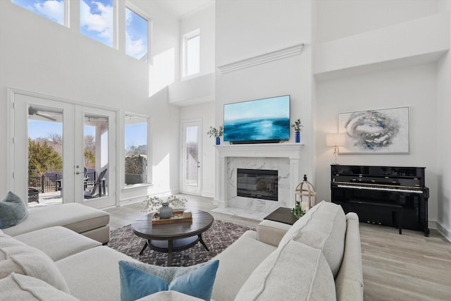 living area featuring a fireplace, baseboards, wood finished floors, and french doors