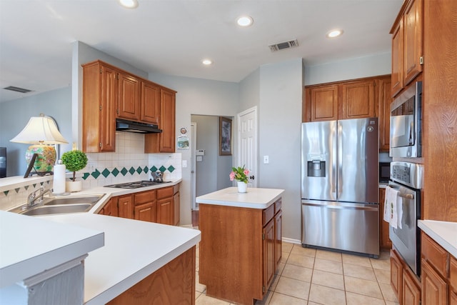 kitchen with visible vents, a kitchen island, stainless steel appliances, under cabinet range hood, and a sink