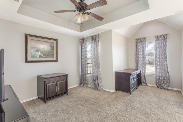 interior space featuring light carpet, a tray ceiling, a ceiling fan, and baseboards