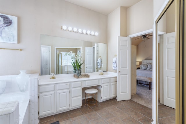 bathroom with a sink, a garden tub, double vanity, and a ceiling fan