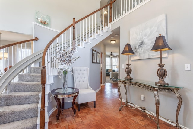 staircase with a high ceiling, baseboards, and a ceiling fan