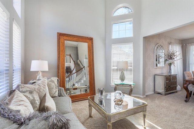 living room with stairs, carpet floors, a towering ceiling, and baseboards