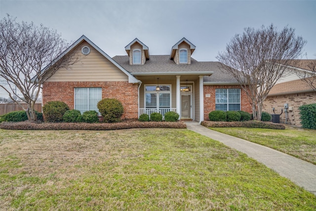 view of front of house featuring brick siding, roof with shingles, and a front yard