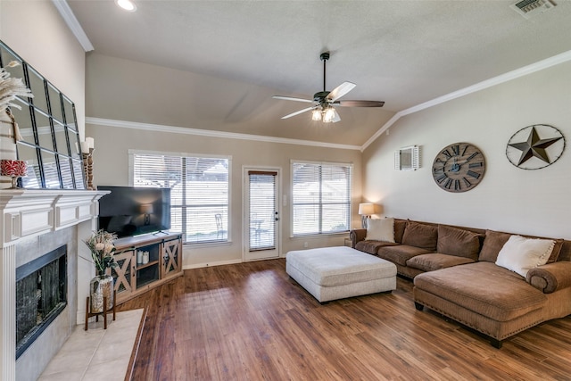 living area with lofted ceiling, ornamental molding, a tile fireplace, and visible vents