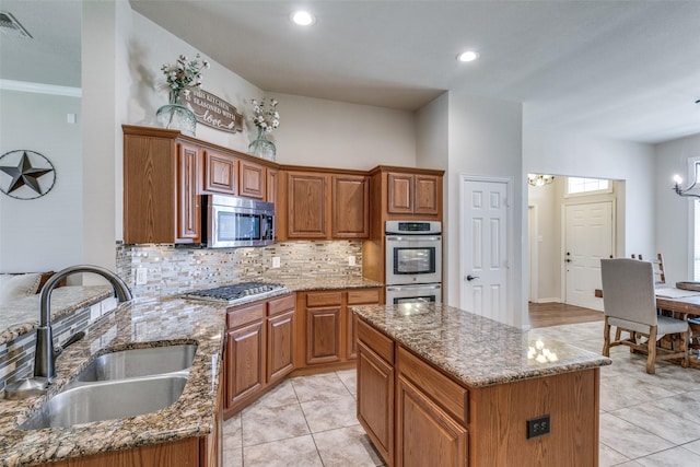 kitchen with stainless steel appliances, stone counters, a sink, and an inviting chandelier