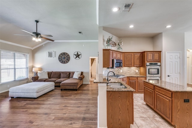 kitchen featuring open floor plan, stainless steel appliances, stone countertops, and visible vents