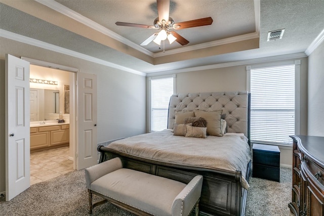 bedroom featuring a textured ceiling, a tray ceiling, visible vents, and crown molding