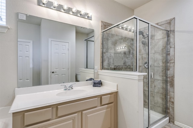 bathroom featuring toilet, a shower stall, and vanity