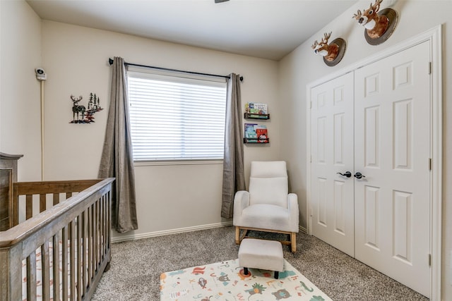 bedroom featuring a crib, baseboards, carpet floors, and a closet