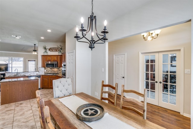 dining room with ceiling fan with notable chandelier, french doors, light tile patterned flooring, and visible vents