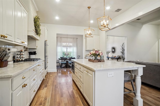 kitchen featuring a breakfast bar area, white cabinetry, open floor plan, and a chandelier