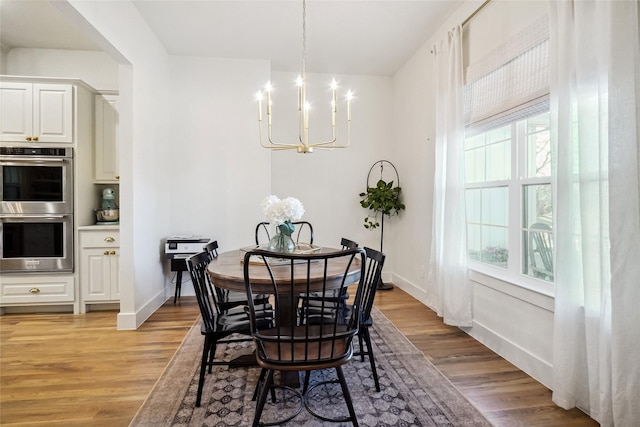 dining room featuring light wood-type flooring, baseboards, and a notable chandelier
