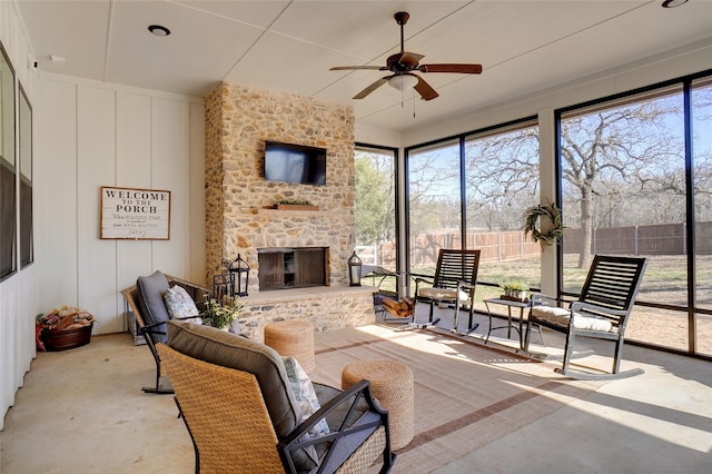 interior space with a fireplace, fence, and ceiling fan