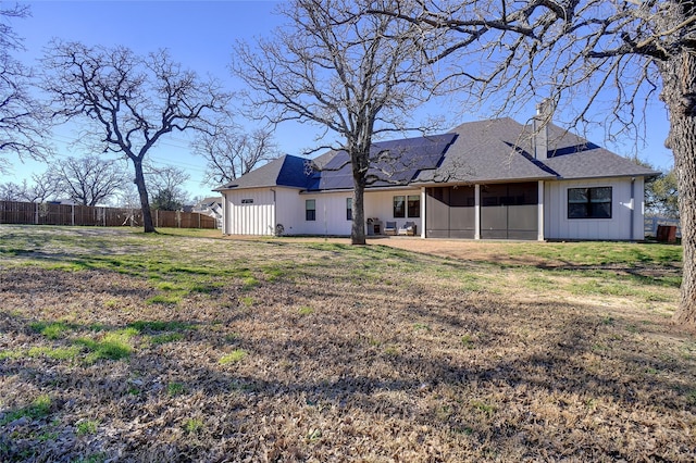 rear view of property with solar panels, fence, a lawn, a sunroom, and a patio