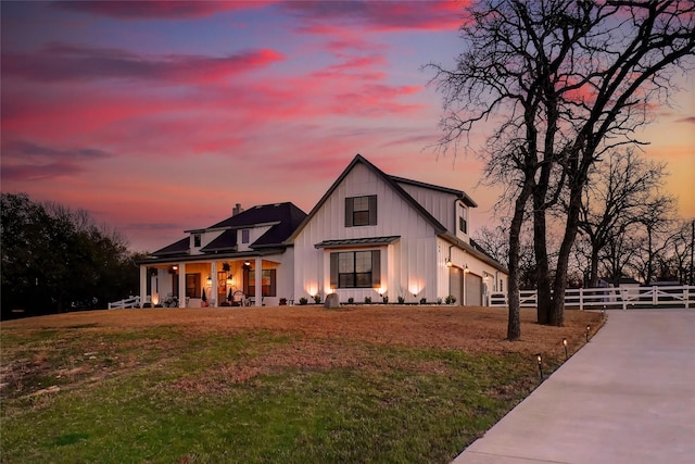 modern farmhouse featuring a lawn, driveway, fence, board and batten siding, and a garage