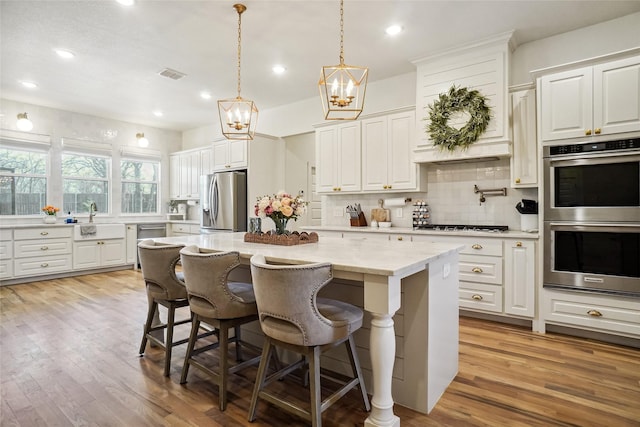 kitchen featuring visible vents, a sink, stainless steel appliances, backsplash, and a chandelier