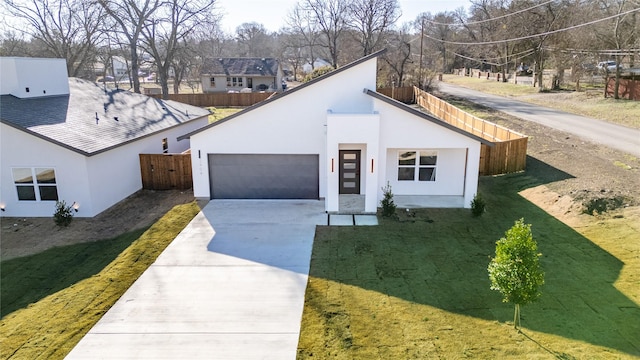 view of front of house featuring a garage, fence, concrete driveway, and stucco siding