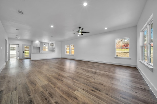 unfurnished living room featuring dark wood-style flooring, plenty of natural light, visible vents, and recessed lighting