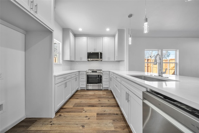 kitchen with dark wood finished floors, a sink, stainless steel appliances, light countertops, and backsplash