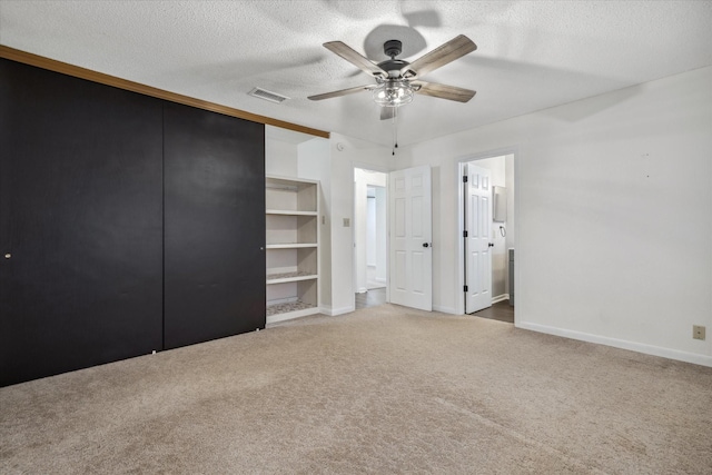 unfurnished bedroom featuring carpet, connected bathroom, visible vents, and a textured ceiling