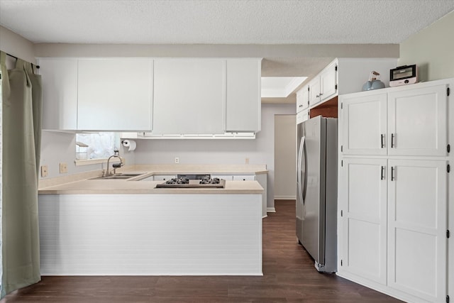 kitchen featuring a peninsula, dark wood-style flooring, a sink, light countertops, and freestanding refrigerator