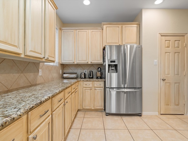 kitchen with light tile patterned floors, light brown cabinetry, and stainless steel fridge