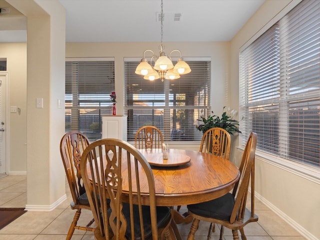 dining space featuring light tile patterned flooring, a notable chandelier, and baseboards