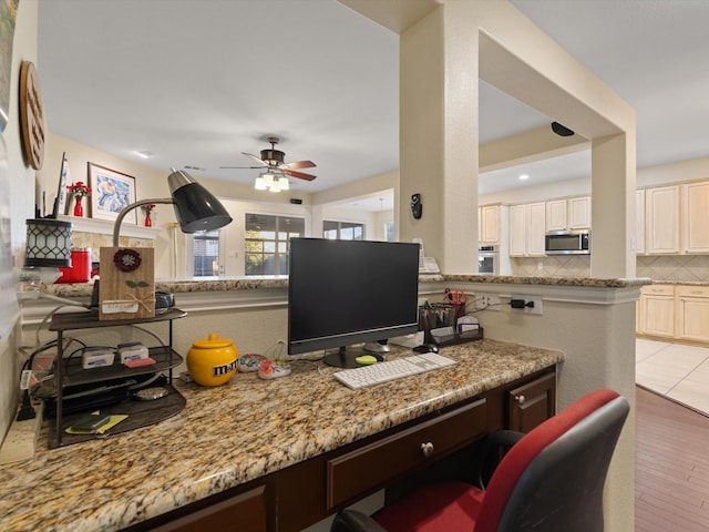 office featuring light wood finished floors, ceiling fan, and built in study area