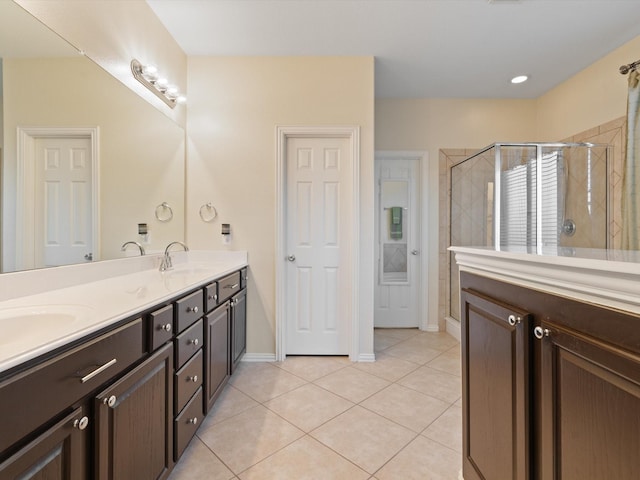 full bathroom with double vanity, a stall shower, a sink, baseboards, and tile patterned floors