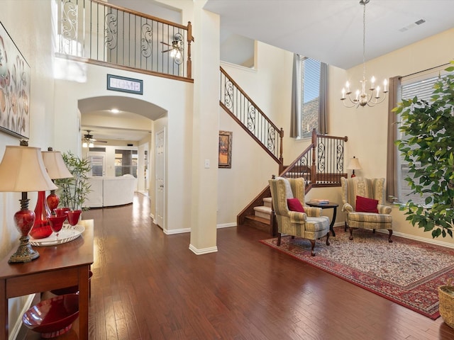 foyer entrance with arched walkways, ceiling fan with notable chandelier, visible vents, stairs, and hardwood / wood-style floors