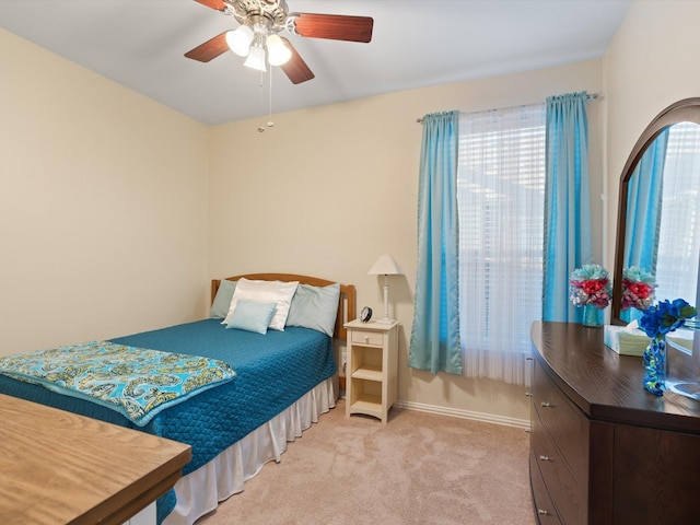 bedroom with a ceiling fan, light carpet, and baseboards