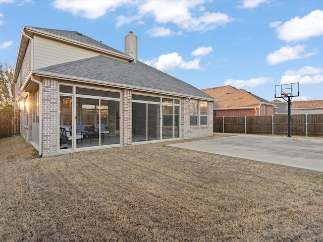 rear view of property featuring a sunroom, a fenced backyard, a patio, and brick siding