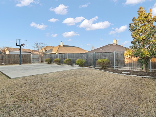 view of yard with basketball court and a fenced backyard