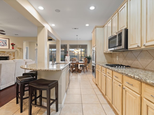 kitchen featuring light brown cabinetry, appliances with stainless steel finishes, a sink, and visible vents