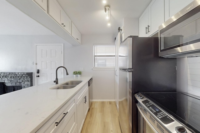 kitchen featuring light wood finished floors, appliances with stainless steel finishes, light countertops, and a sink