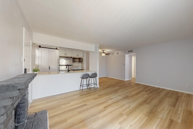 living room featuring light wood-style floors, a fireplace, ceiling fan, and visible vents