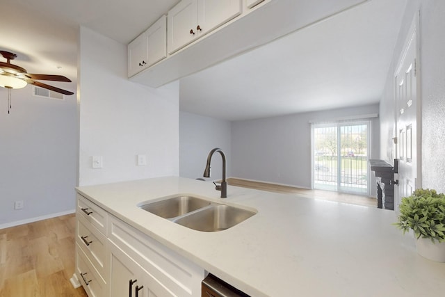 kitchen with visible vents, white cabinets, light countertops, light wood-type flooring, and a sink