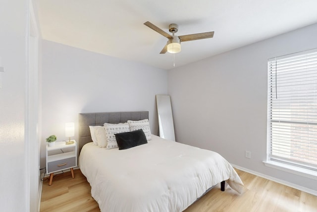 bedroom featuring ceiling fan, light wood-style flooring, and baseboards